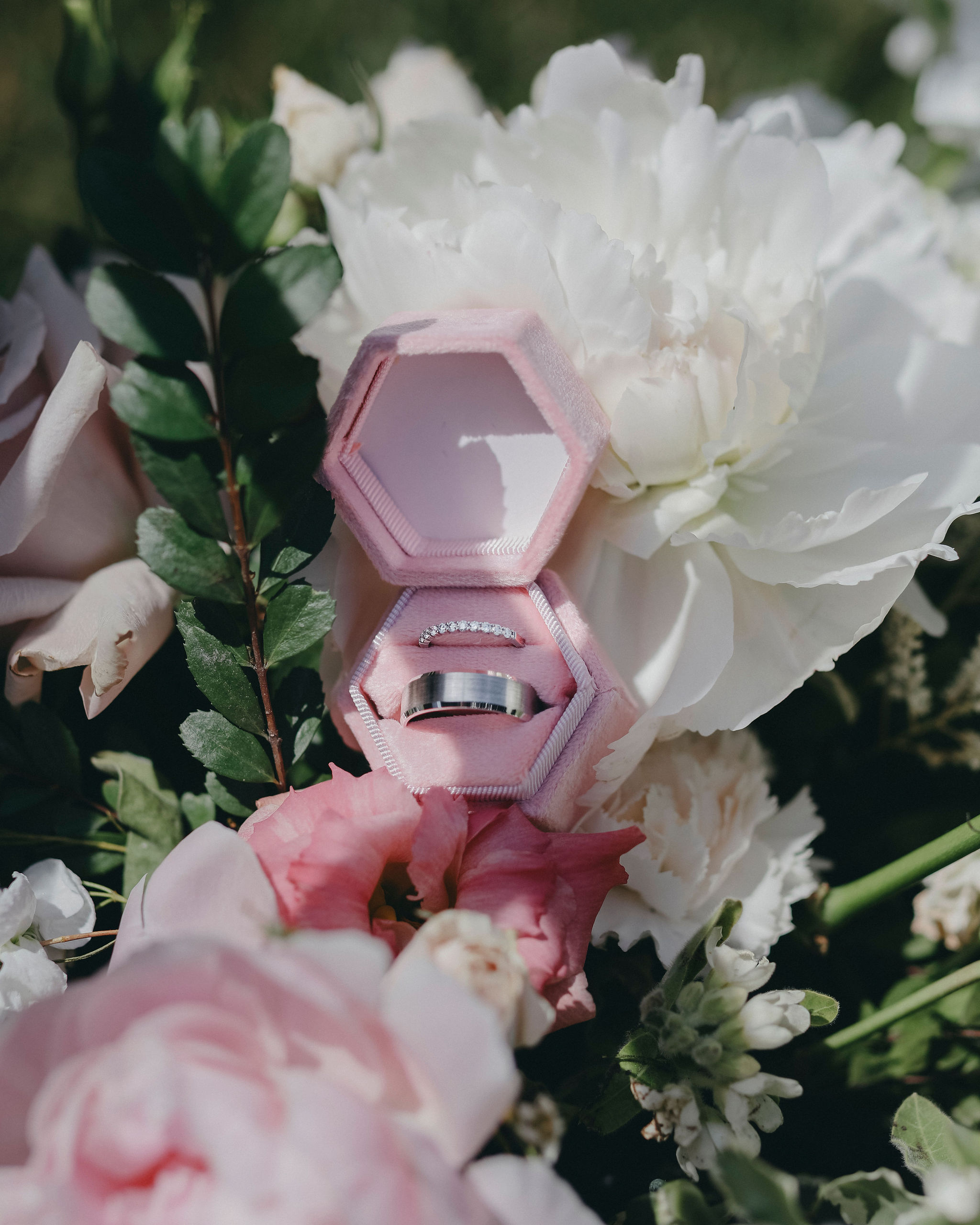 Ring in a pink ring box sitting in white and pink flowers.
